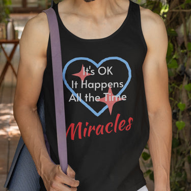 Lightweight Bella+Canvas tank top made from preshrunk cotton with “Miracles Happen” design message, “It’s OK. It Happens All the Time – Miracles,” inspirational apparel encouraging daily miracles through intimacy with God, man in black tank top
